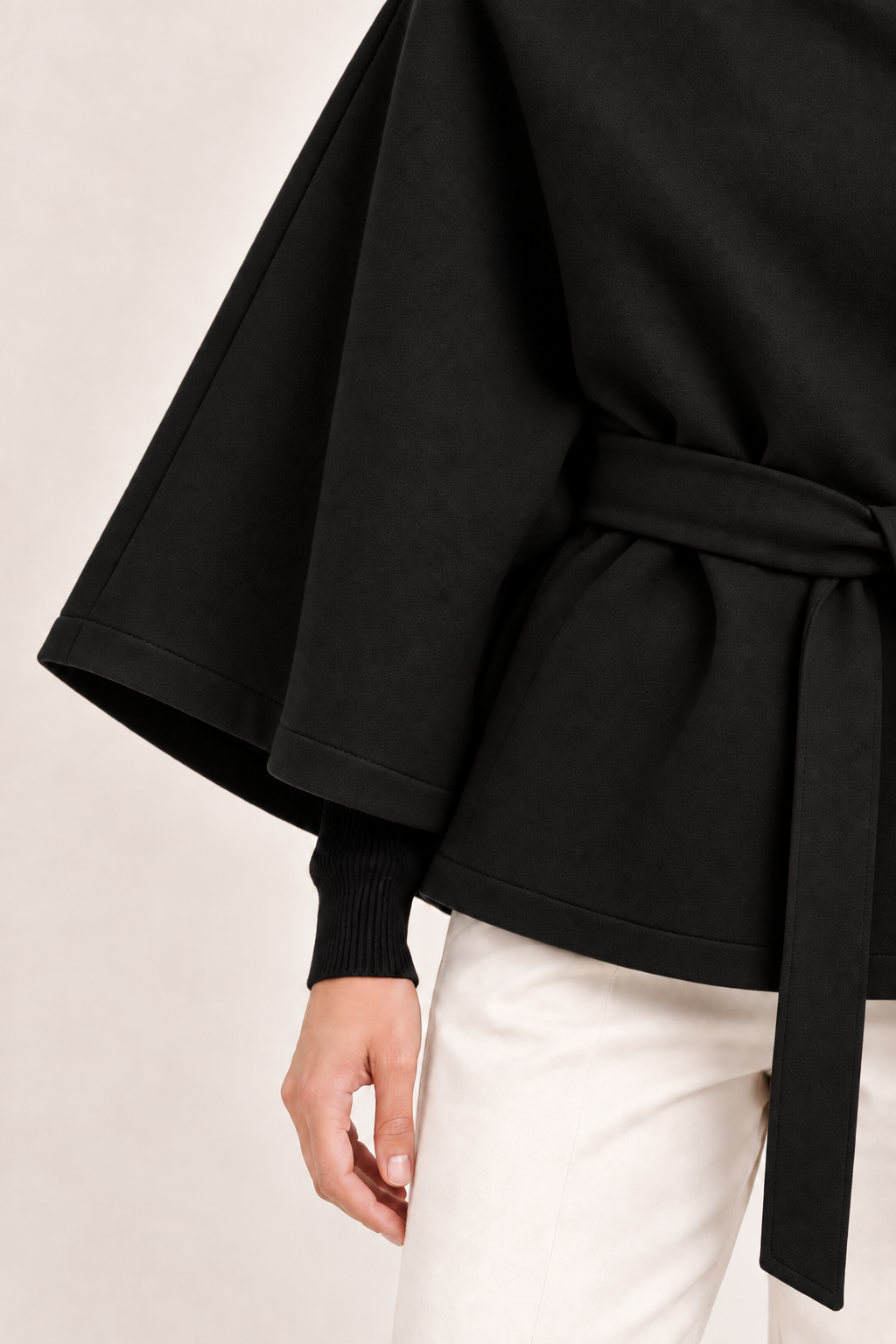 Capa de cuello alto y cinturón Valorenne en negro, detalle de la manga, el dobladillo y el tejido