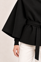 Capa de cuello alto y cinturón Valorenne en negro, detalle de la manga, el dobladillo y el tejido