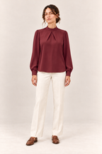 Blusa satinada con cuello alto y pliegues en burdeos, vista frontal de estudio