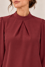 Blusa satinada con cuello alto y pliegues en burdeos, detalle del cuello y los pliegues