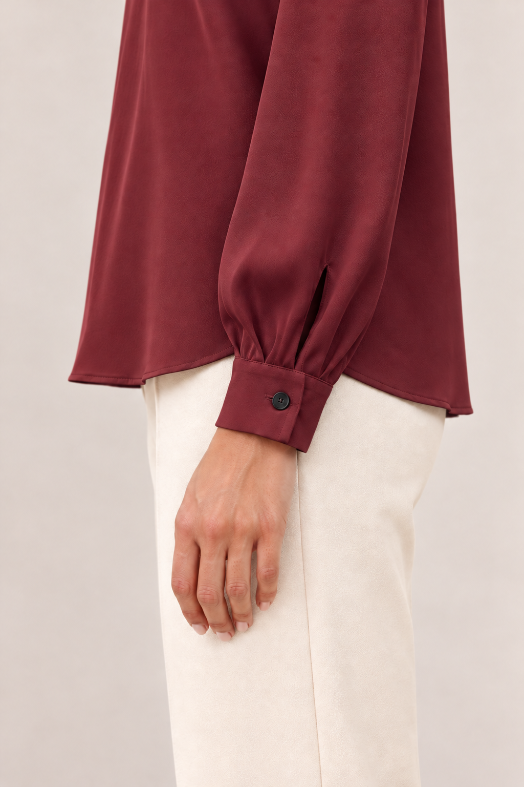 Blusa satinada con cuello alto y pliegues en burdeos, detalle del puño