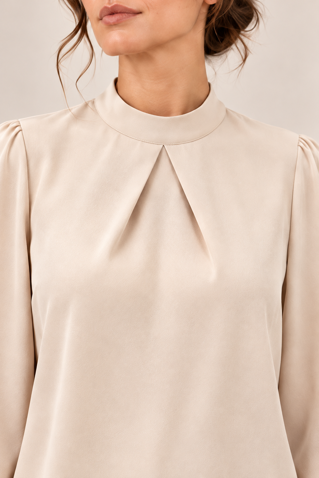 Blusa satinada con cuello alto y pliegues en marfil, detalle del cuello y los pliegues