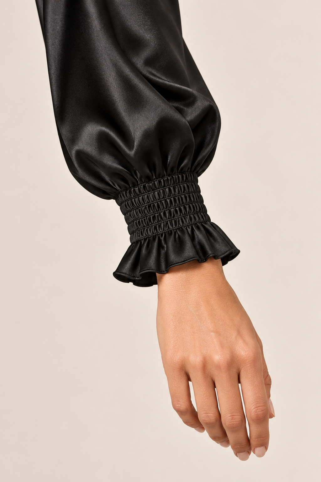 Blusa satinada en negro, detalle del puño fruncido y volante