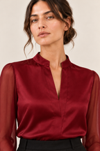 Blusa satinada con mangas transparentes en burdeos, detalle del cuello y la abertura frontal