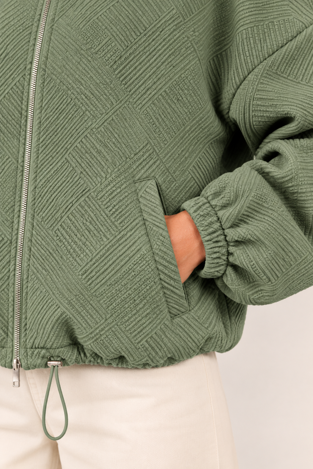 Chaqueta bomber de cuello alto en verde militar, detalle del tejido y el bolsillo