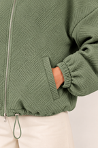 Chaqueta bomber de cuello alto en verde militar, detalle del tejido y el bolsillo