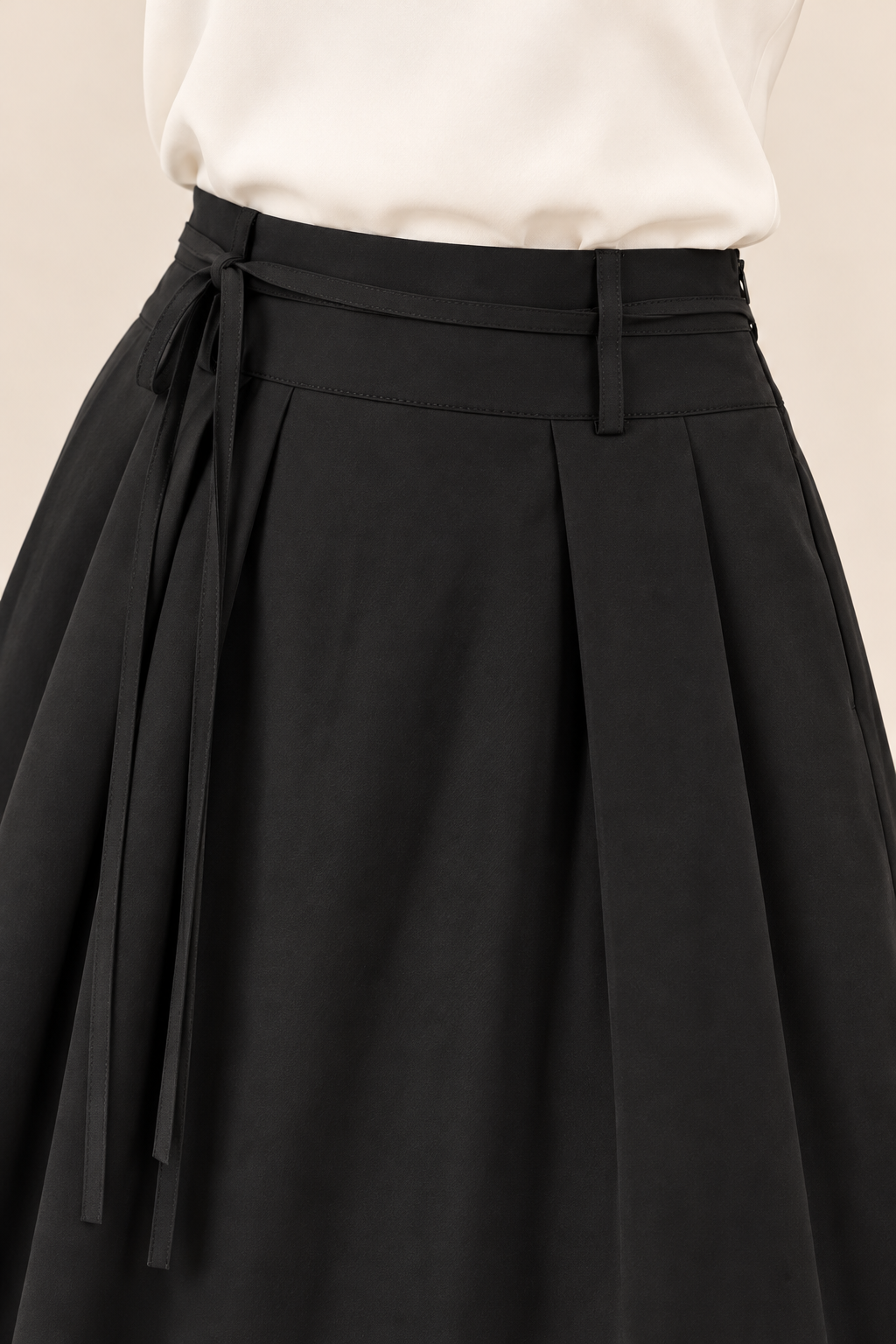 Falda larga de pinzas con bolsillos en negro, detalle de la cintura y la lazada