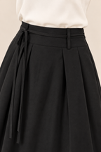 Falda larga de pinzas con bolsillos en negro, detalle de la cintura y la lazada