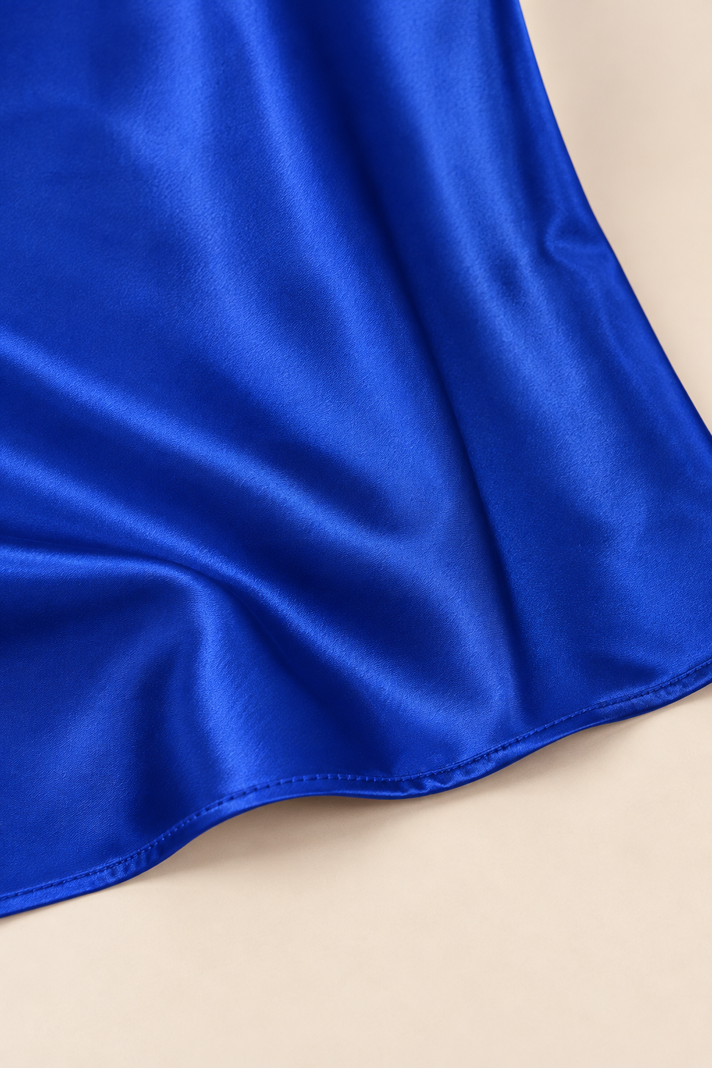 Falda satinada con abertura en azul, detalle del tejido y el bajo