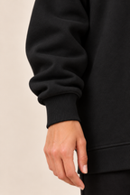 Jersey con cremallera lateral en negro, detalle del puño