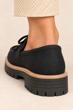 Mocasines con lazo y flecos en negro, detalle del talón y la suela