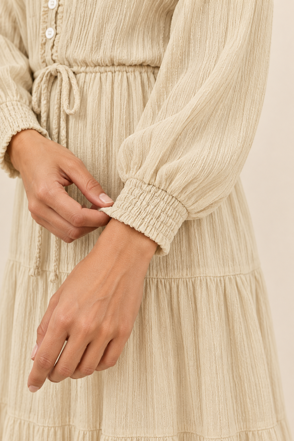 Vestido midi con lazada y botones en crudo, detalle de la textura y el puño fruncido